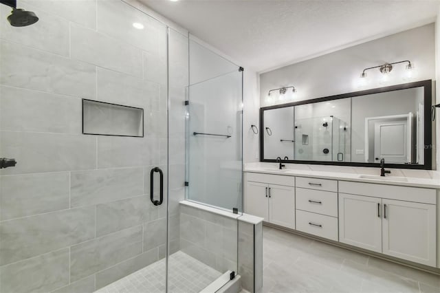 bathroom with tile patterned floors, a shower with door, vanity, and a textured ceiling