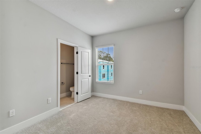 unfurnished bedroom featuring connected bathroom and light colored carpet