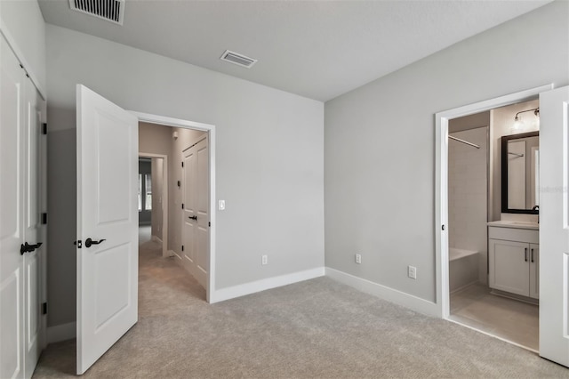 unfurnished bedroom with light colored carpet and ensuite bath