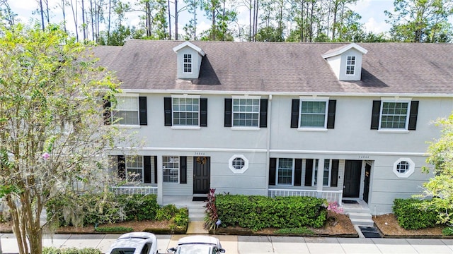 multi unit property with roof with shingles and stucco siding