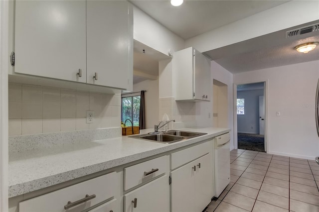 kitchen with white dishwasher, sink, white cabinetry, and light tile patterned floors