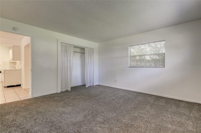 unfurnished bedroom featuring light carpet, a textured ceiling, and a closet