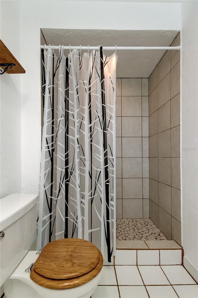 bathroom featuring tile patterned flooring, toilet, and curtained shower