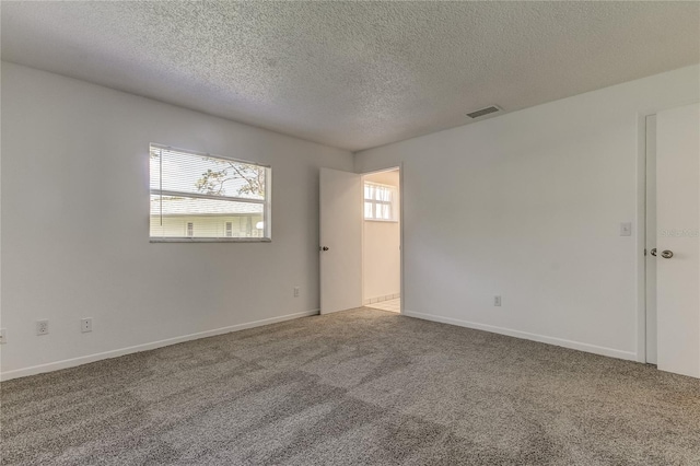 carpeted empty room featuring a textured ceiling