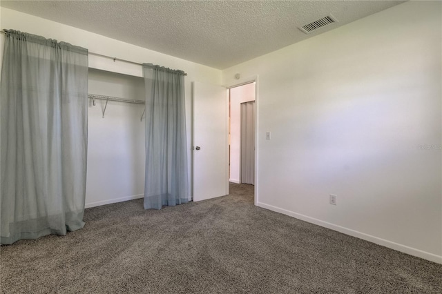 unfurnished bedroom featuring dark colored carpet, a textured ceiling, and a closet