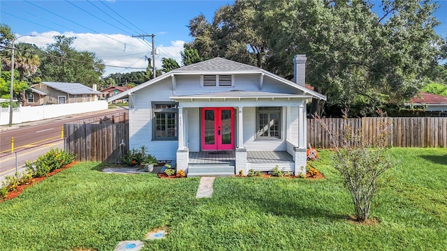 bungalow-style house with a front lawn and french doors