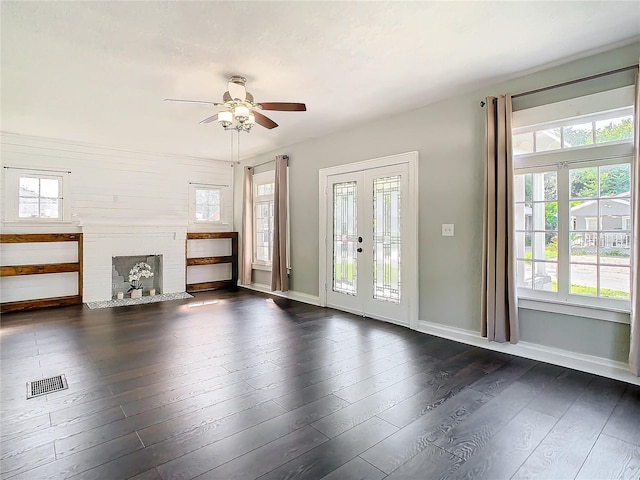 unfurnished living room featuring dark hardwood / wood-style floors, ceiling fan, french doors, and a brick fireplace