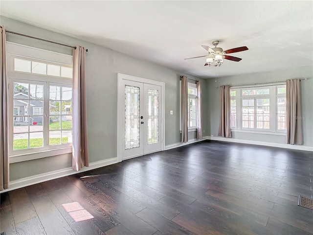 interior space with a wealth of natural light, dark wood-type flooring, ceiling fan, and french doors