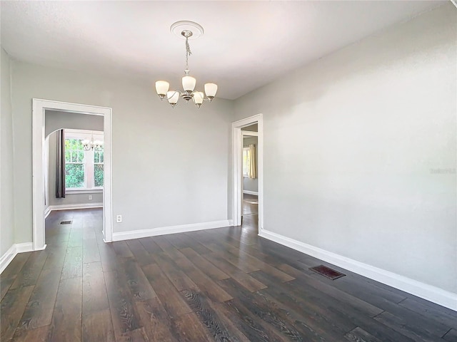 empty room with dark hardwood / wood-style flooring and a notable chandelier