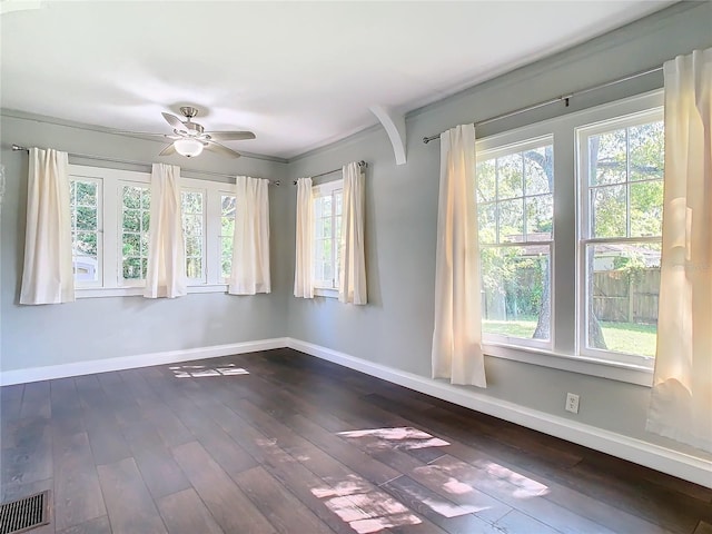 unfurnished room featuring ornamental molding, dark hardwood / wood-style flooring, ceiling fan, and plenty of natural light