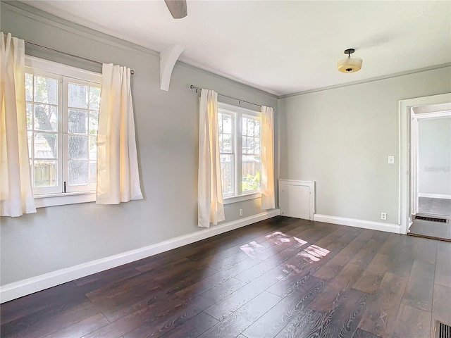 empty room featuring a healthy amount of sunlight, crown molding, and dark hardwood / wood-style floors