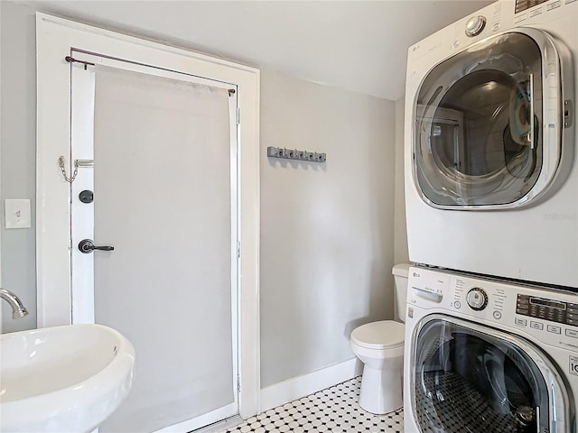 washroom with stacked washer and dryer, light tile patterned flooring, and sink