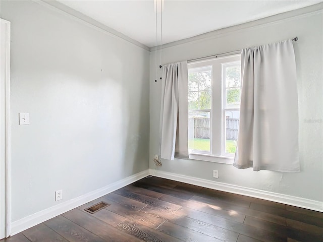 spare room featuring dark hardwood / wood-style floors and crown molding