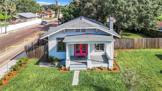 bungalow featuring covered porch and a front yard