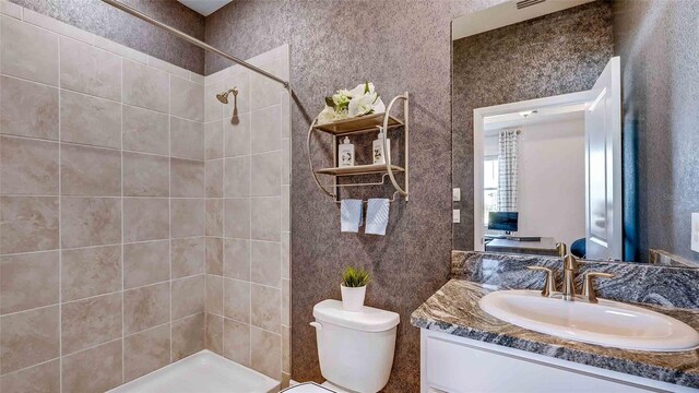 bathroom featuring tiled shower, vanity, and toilet