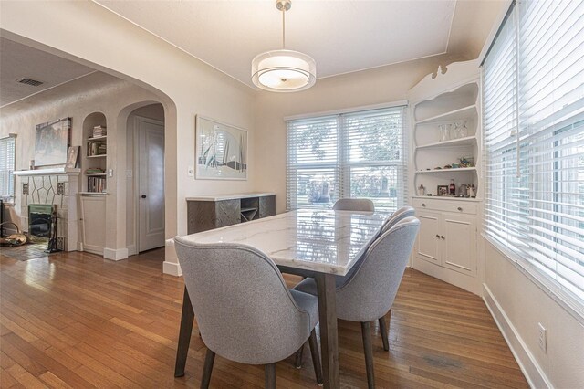 dining space with built in shelves, hardwood / wood-style floors, and a fireplace