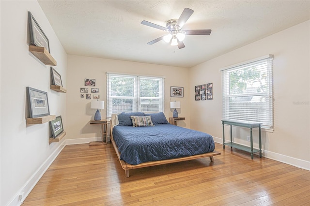 bedroom with light wood-type flooring, a textured ceiling, and ceiling fan