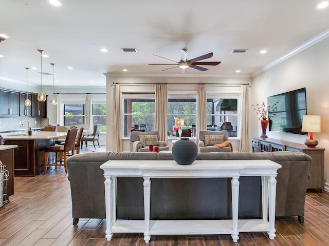 living room featuring crown molding, dark hardwood / wood-style floors, ceiling fan, and sink