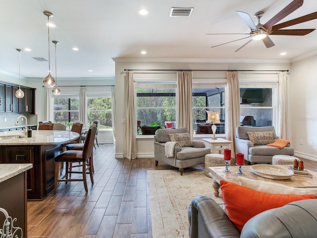 living room featuring crown molding, ceiling fan, dark wood-type flooring, and plenty of natural light