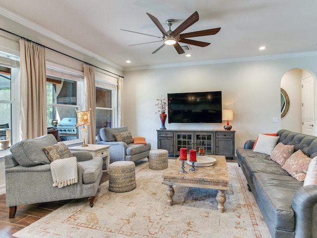 living room featuring wood-type flooring, ornamental molding, and ceiling fan