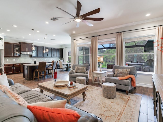 living room with crown molding, dark hardwood / wood-style floors, and ceiling fan