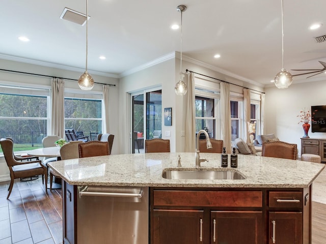 kitchen featuring pendant lighting, sink, an island with sink, light hardwood / wood-style flooring, and ornamental molding