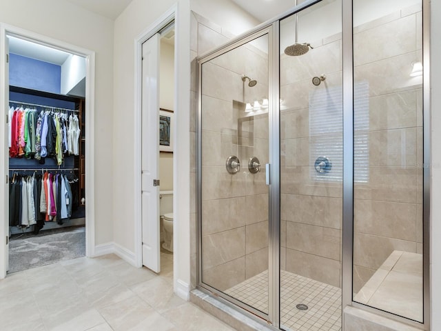 bathroom with tile patterned flooring, toilet, and a shower with door