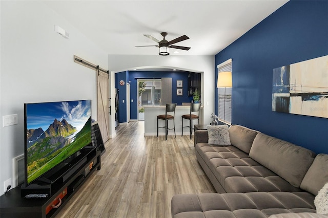 living room with ceiling fan, hardwood / wood-style flooring, and a barn door