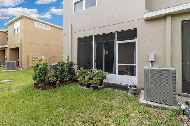 back of property with a sunroom, a yard, and central AC