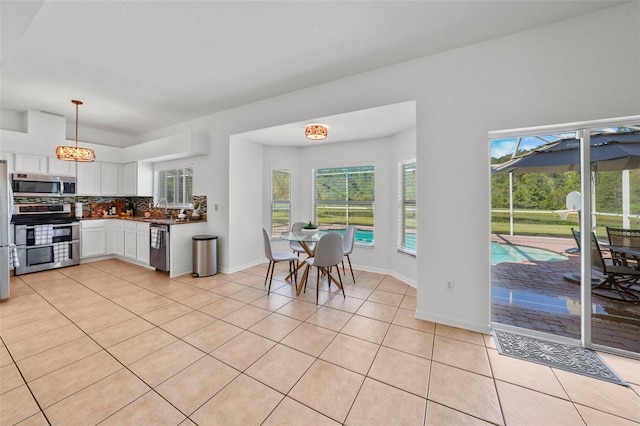 kitchen with appliances with stainless steel finishes, light tile patterned floors, white cabinetry, and sink