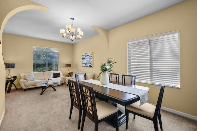 carpeted dining room with an inviting chandelier