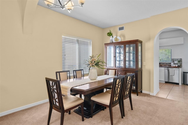 carpeted dining area with a chandelier