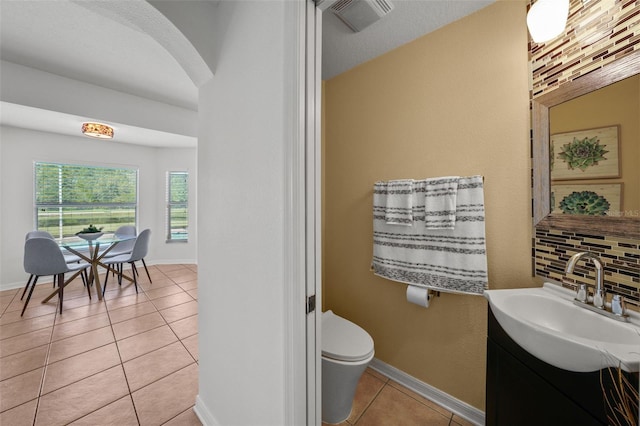 bathroom featuring toilet, decorative backsplash, vanity, and tile patterned floors