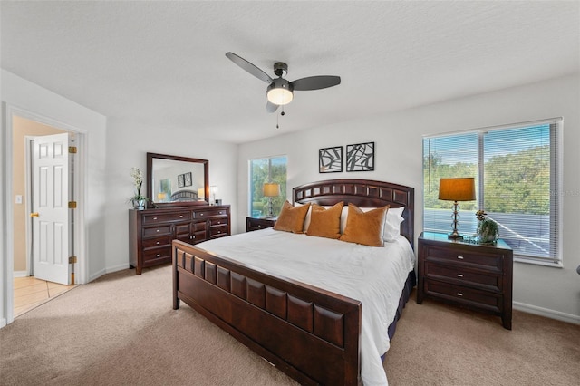 carpeted bedroom featuring multiple windows, a textured ceiling, and ceiling fan