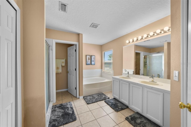 bathroom with tile patterned flooring, vanity, a textured ceiling, and independent shower and bath