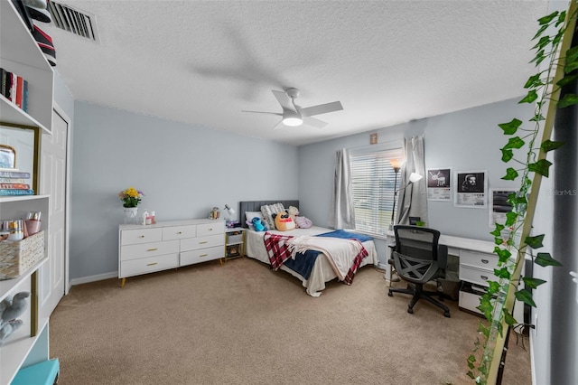 bedroom with ceiling fan, light carpet, and a textured ceiling