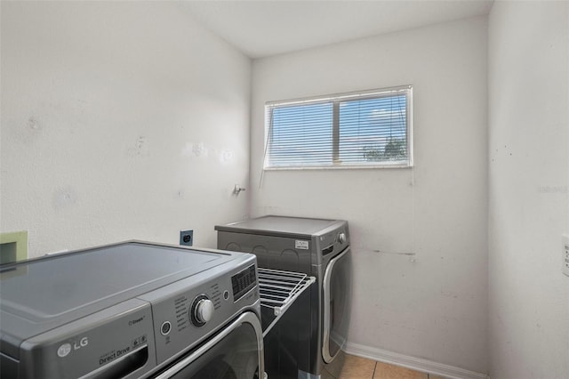 laundry area with washer and clothes dryer and light tile patterned flooring