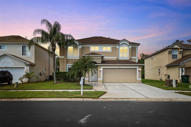 view of property with a yard, central AC unit, and a garage