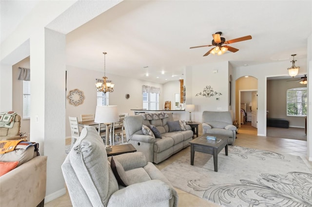 tiled living room featuring a healthy amount of sunlight and ceiling fan with notable chandelier