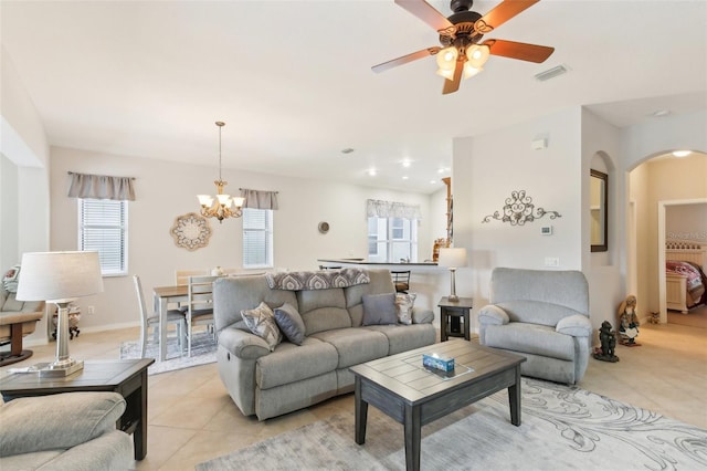 tiled living room with ceiling fan with notable chandelier