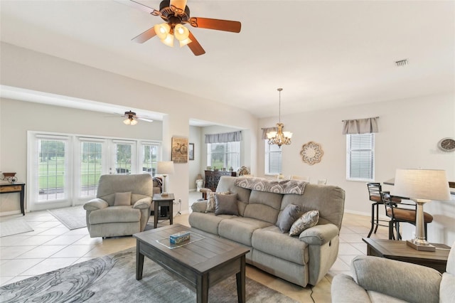 living room with light tile patterned floors, plenty of natural light, and ceiling fan with notable chandelier