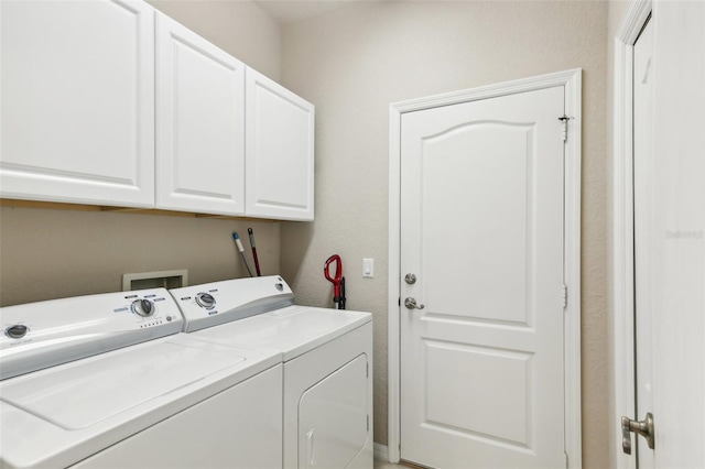 clothes washing area featuring cabinets and separate washer and dryer