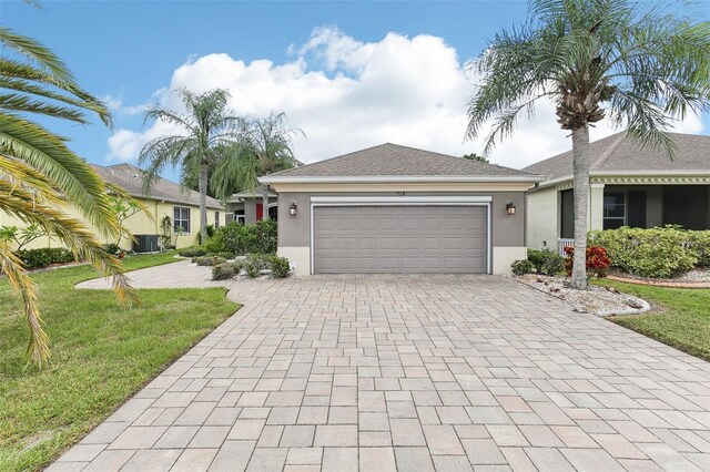 ranch-style home featuring decorative driveway, a garage, a front yard, and stucco siding
