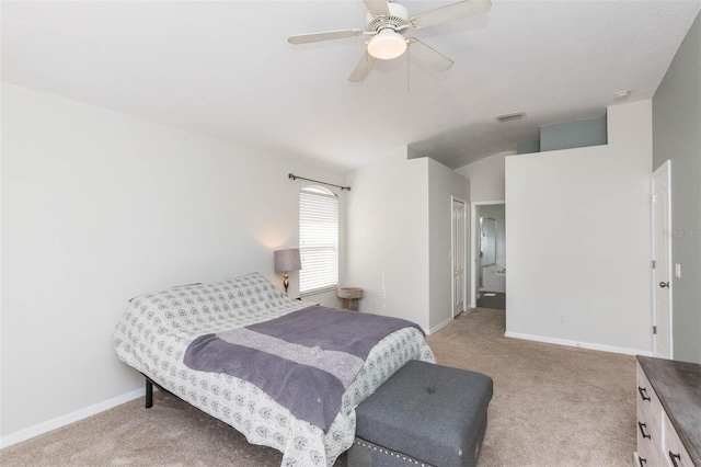 bedroom with ceiling fan, light colored carpet, and ensuite bathroom