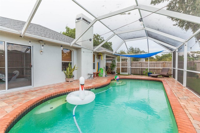 view of swimming pool featuring a patio and glass enclosure