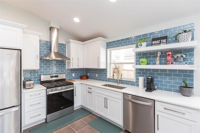 kitchen featuring wall chimney range hood, sink, appliances with stainless steel finishes, tasteful backsplash, and white cabinetry