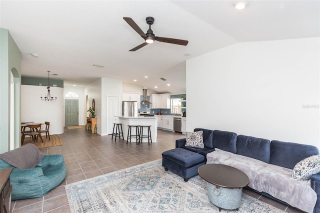 living room with tile patterned floors, ceiling fan with notable chandelier, sink, and vaulted ceiling