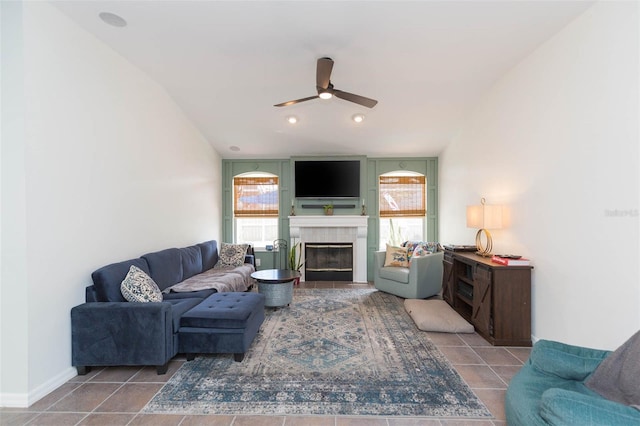 living room with ceiling fan, a tile fireplace, and vaulted ceiling