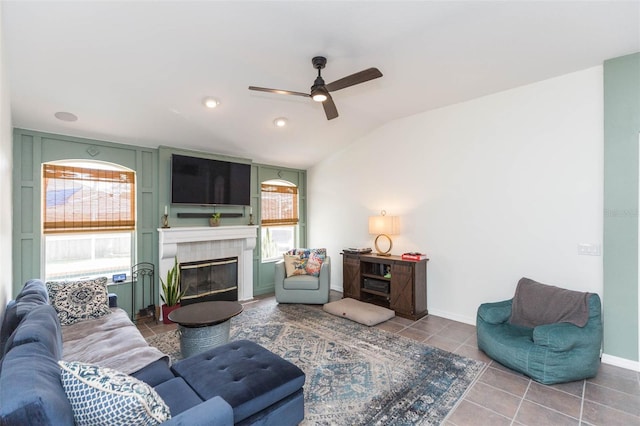 tiled living room with a tile fireplace, ceiling fan, a healthy amount of sunlight, and lofted ceiling