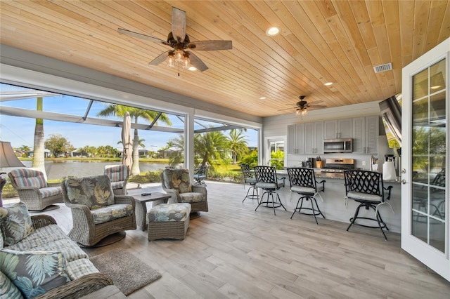 sunroom / solarium featuring wood ceiling, ceiling fan, a water view, and a wealth of natural light